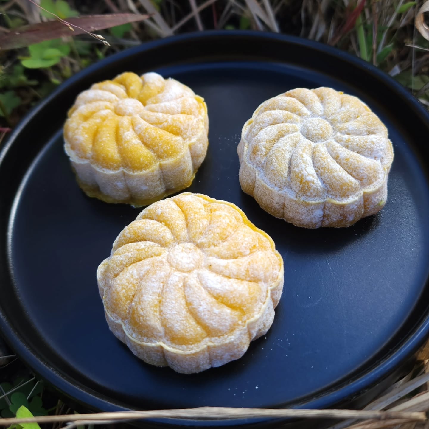 Three orange mooncakes on a black plate